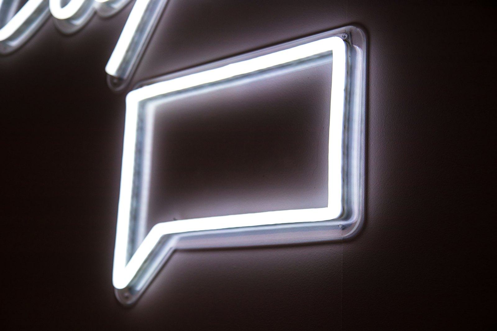 A white neon speech bubble glowing on a dark wall